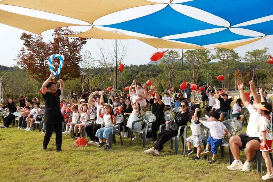 파라솔이 늘어선 야외 관람석에서 공연을 지켜보는 축제 방문객들