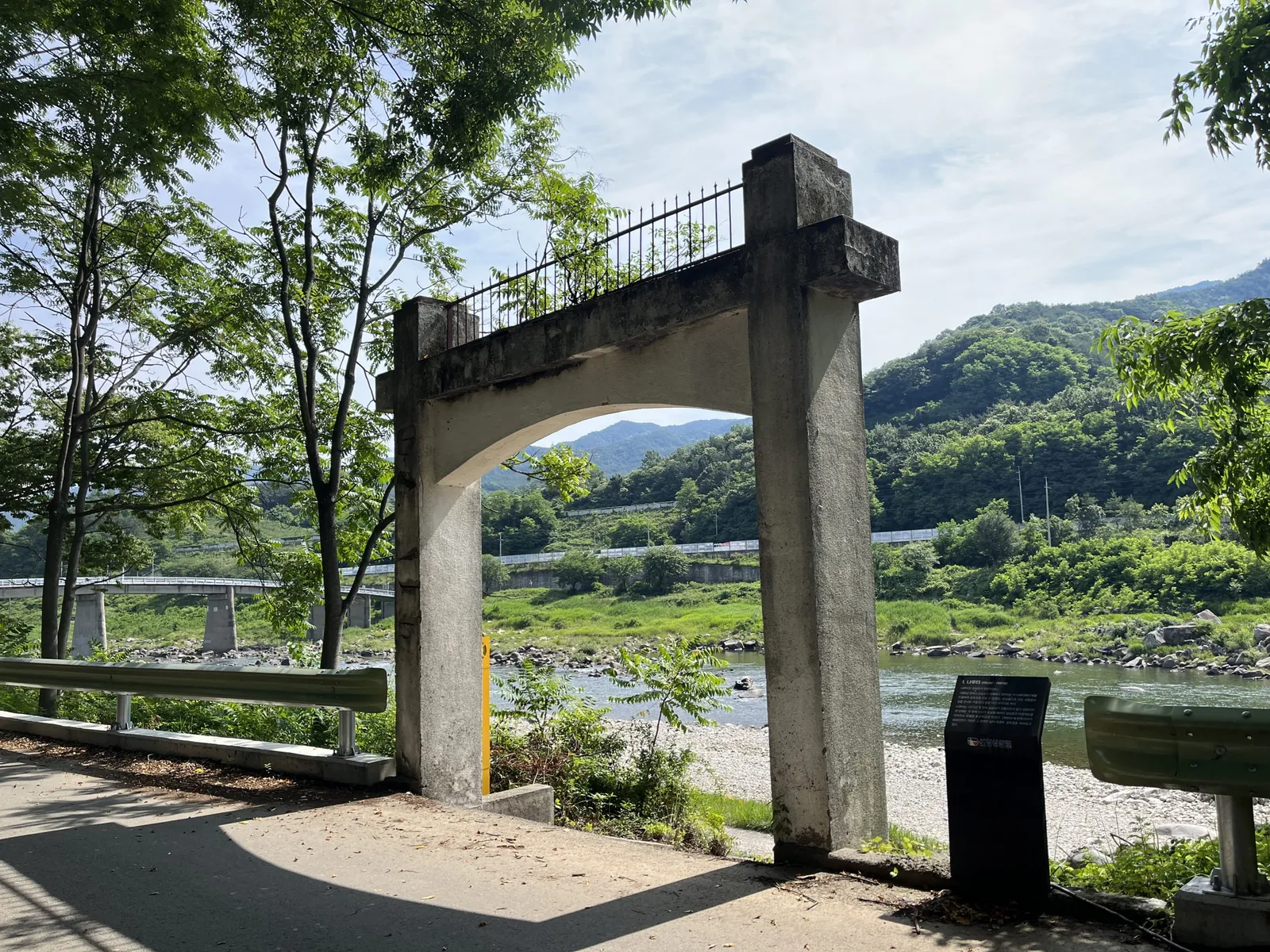 경호강변에 세워진 지리산둘레길 나루터 표지 아치, 뒤로 강과 야산이 보인다