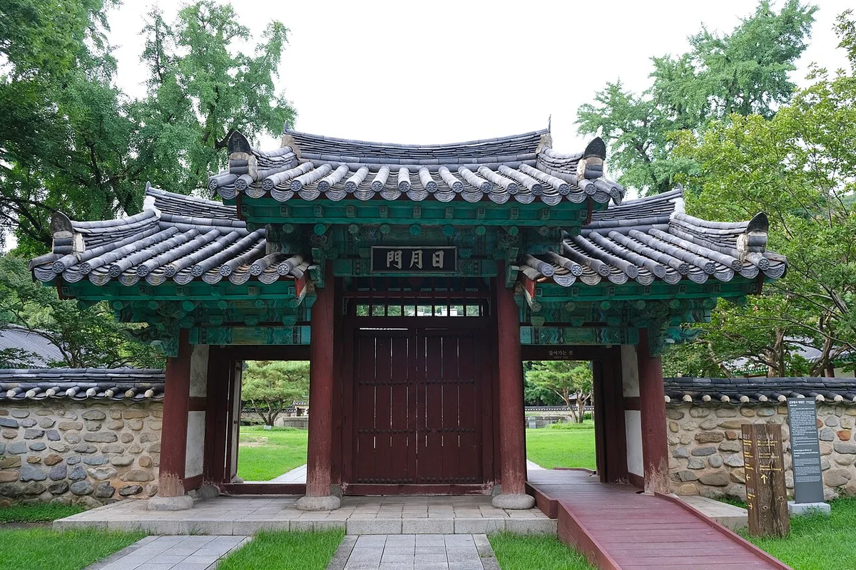 붉은 기둥과 녹색 단청 처마를 가진 문과 주변의 큰 나무들