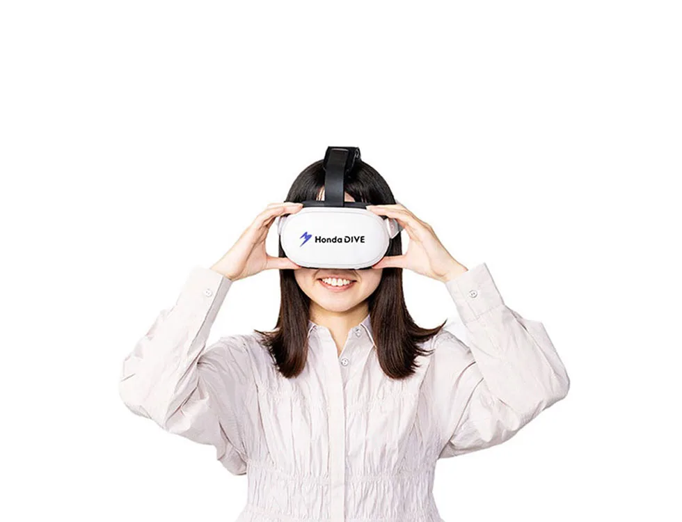 VR 헤드셋 앞면에 혼다 DIVE 로고가 보이는 헤드셋을 쓰려는 사람
