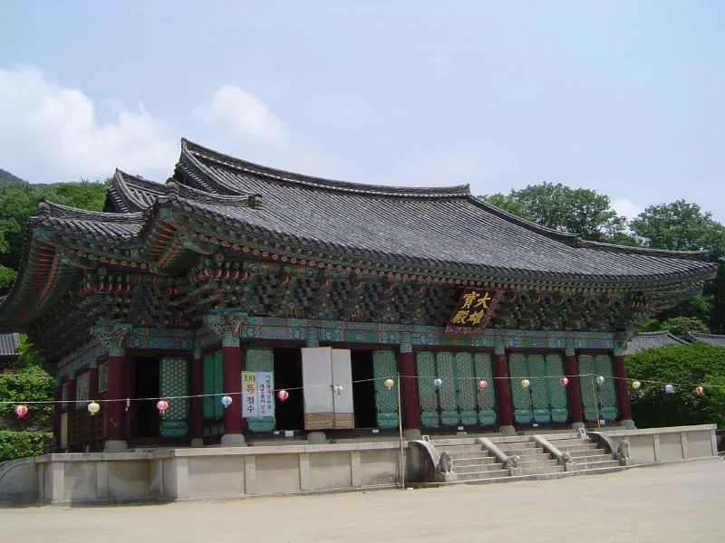 석탑과 석등이 놓인 송광사 넓은 마당, 뒤로 여러 채의 전각과 산이 보이는 전경