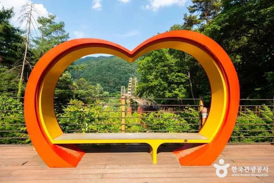 하트 모양 주황색 조형물과 그 너머로 산이 보이는 쉼터