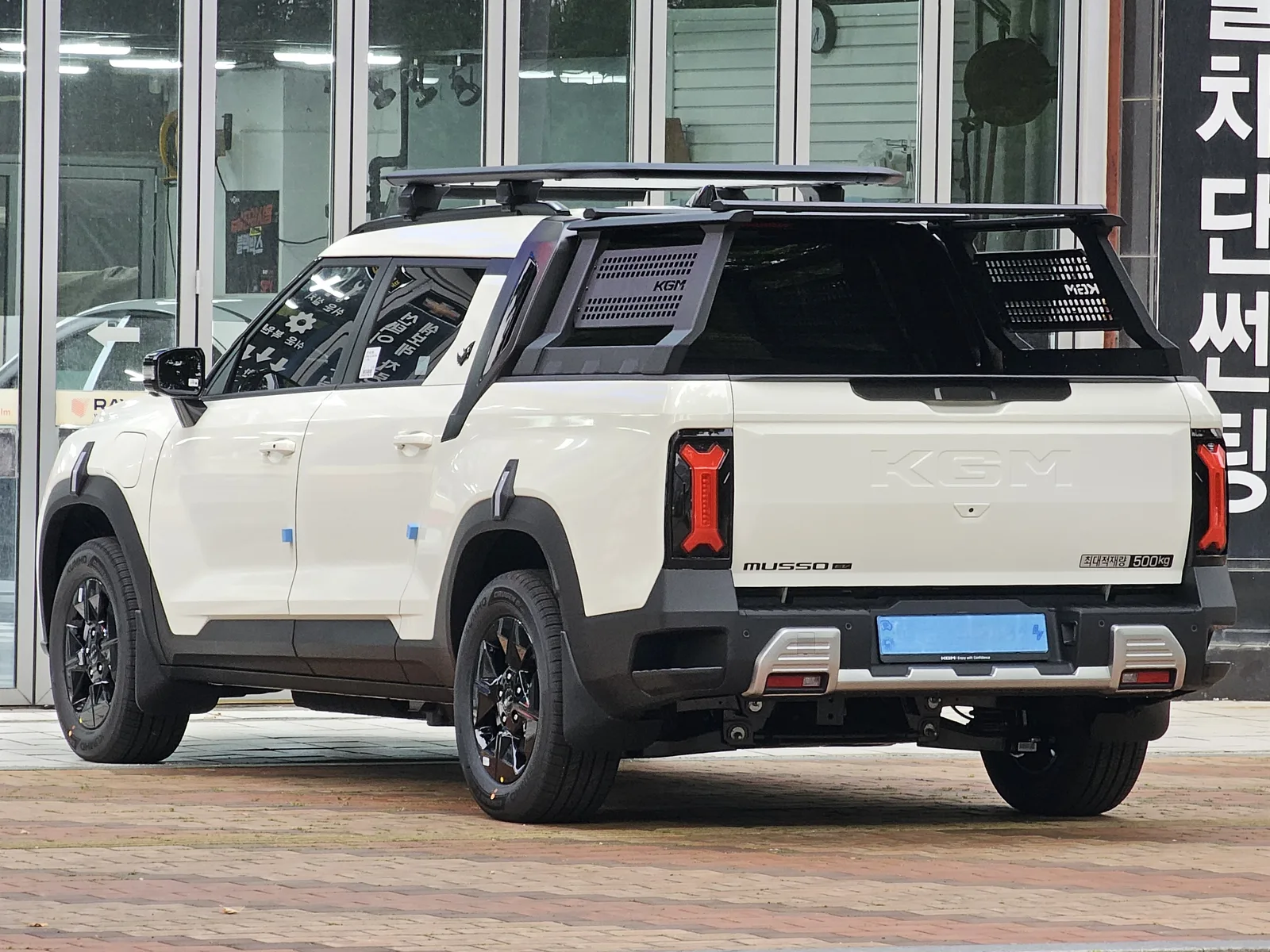 KGM 무쏘 EV 픽업트럭의 후측면, 적재함에 MUSSO EV 로고와 최대적재량 500kg 표기, 테일게이트에 KGM 배지가 보인다