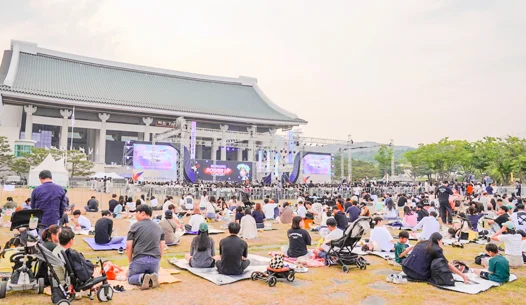 독립기념관 겨레의집 앞 잔디밭에 앉아 공연을 관람하는 관람객들