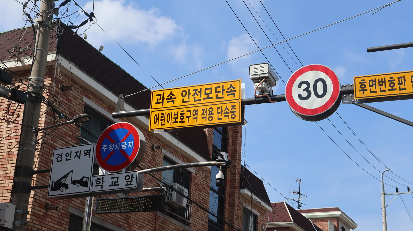 경기도 안산시 신길중앙로 어린이보호구역 표지판과 과속·안전모 무인단속 카메라, 제한속도 30km 표지판이 함께 설치된 모습