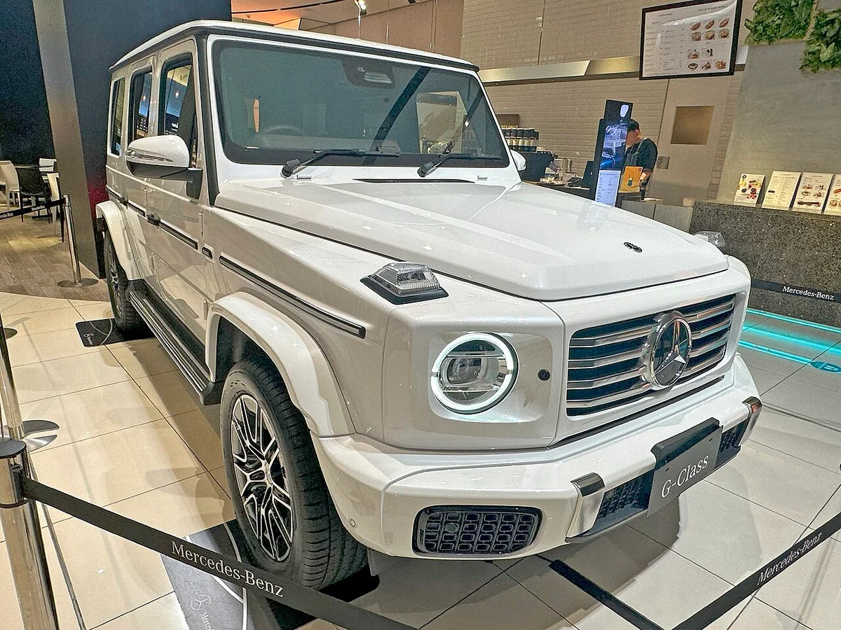 흰색 메르세데스-벤츠 G 450 d 런치 에디션의 전면과 측면, 둥근 헤드램프와 수직 그릴이 보인다