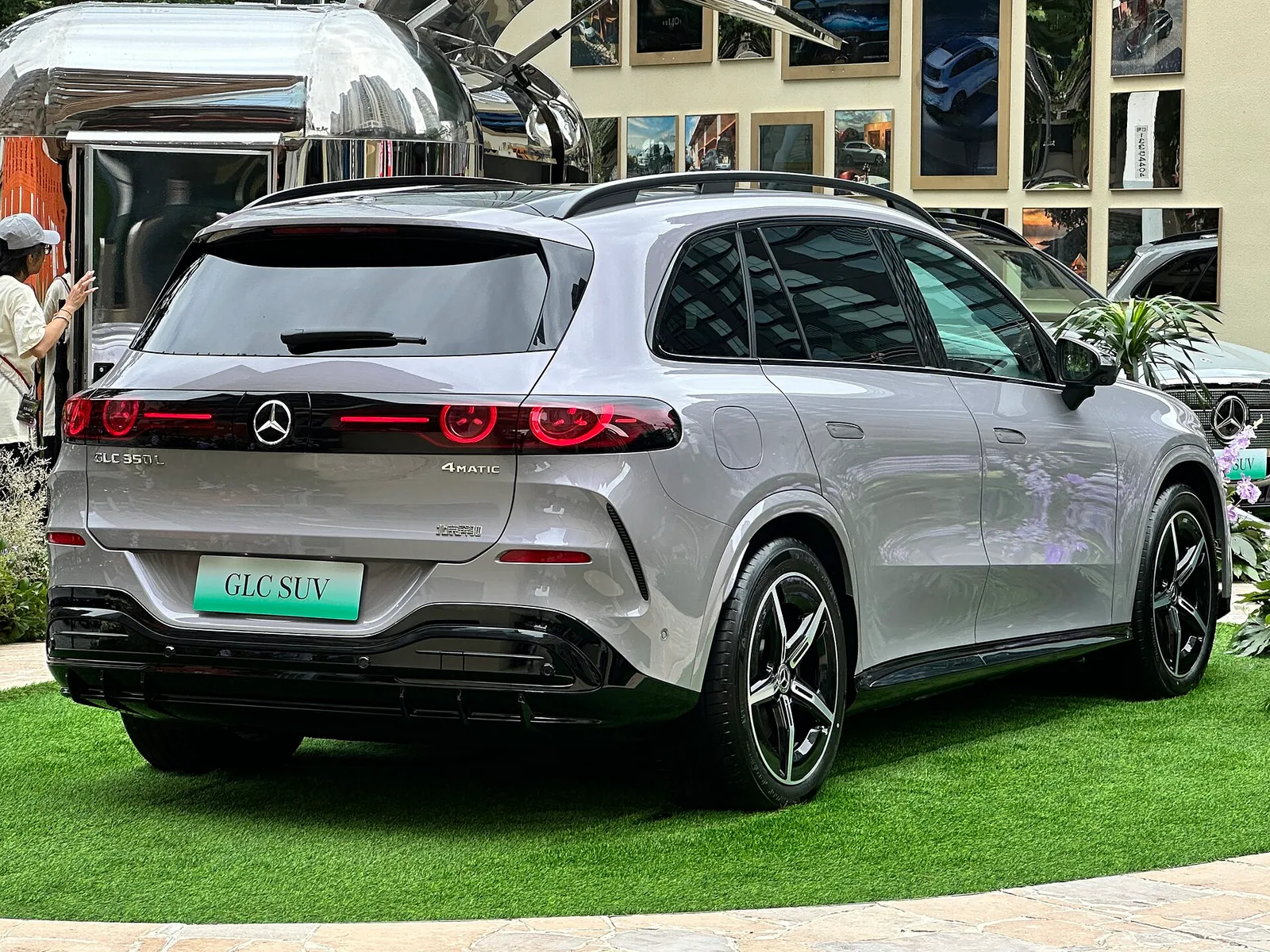 회색 메르세데스-벤츠 GLC SUV 전기차의 후면, 가로로 이어진 테일램프와 4MATIC 배지