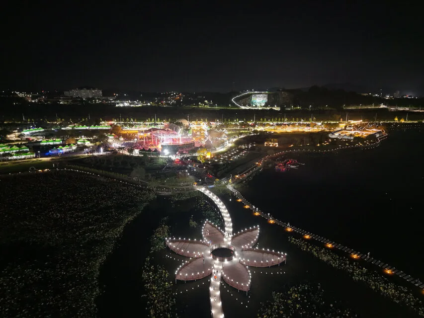 밤에 조명이 켜진 나주 영산강정원 축제장 전경, 강 위에 꽃 모양 야간 조명 데크가 떠 있다