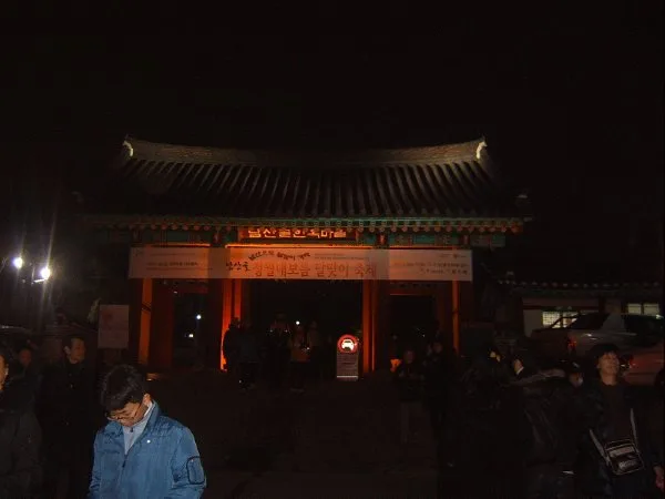 야간 조명이 밝혀진 남산골한옥마을 정문, 붉은 등과 현수막이 걸려 축제 분위기를 낸다