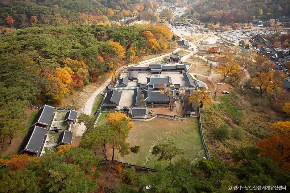 붉게 물든 숲 사이에 기와 건물이 모여 있는 남한산성 행궁 일대