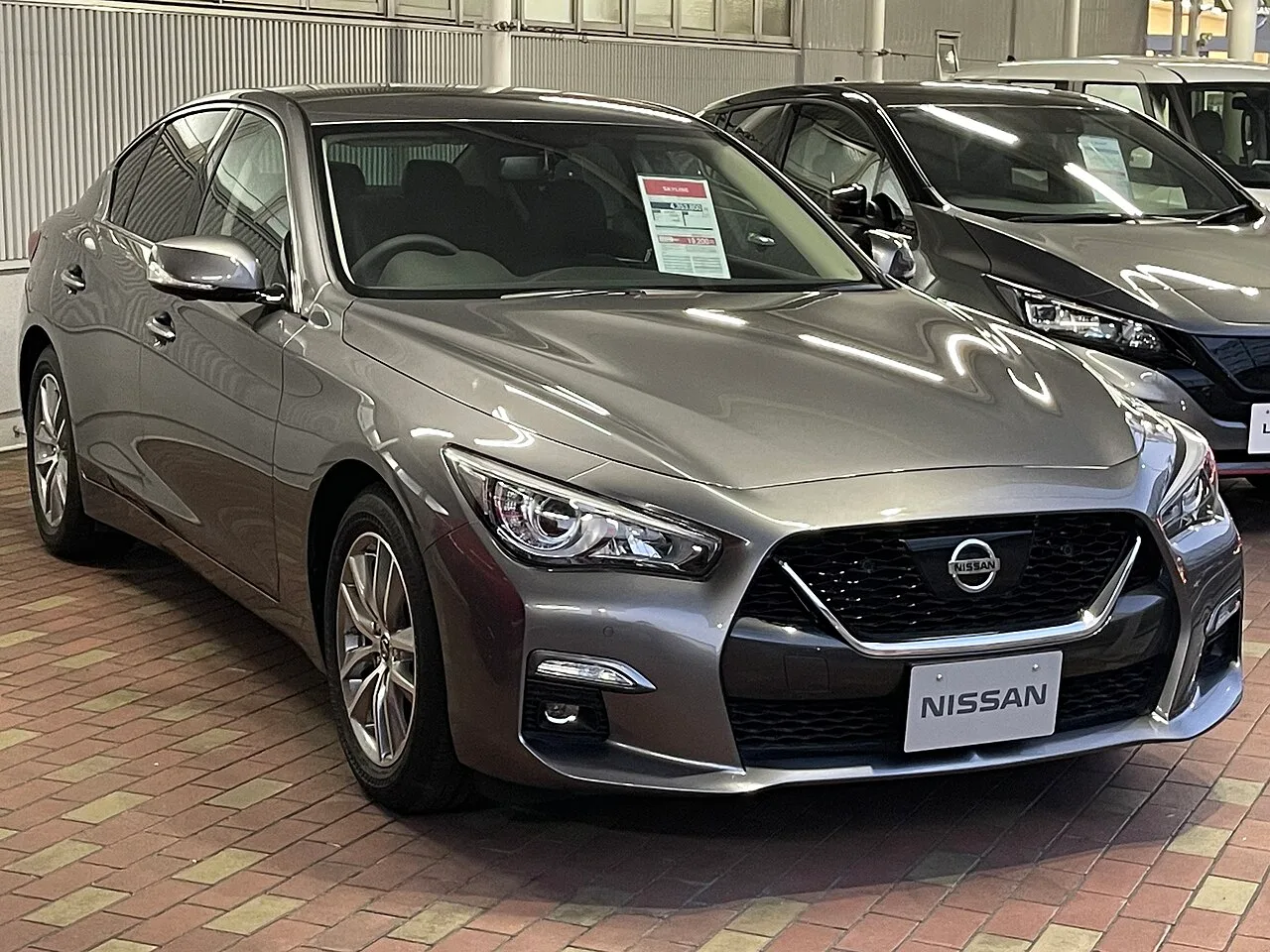 닛산 전시장에 놓인 현행 스카이라인(V37)의 전면 및 측면 모습, NISSAN 배지가 보인다