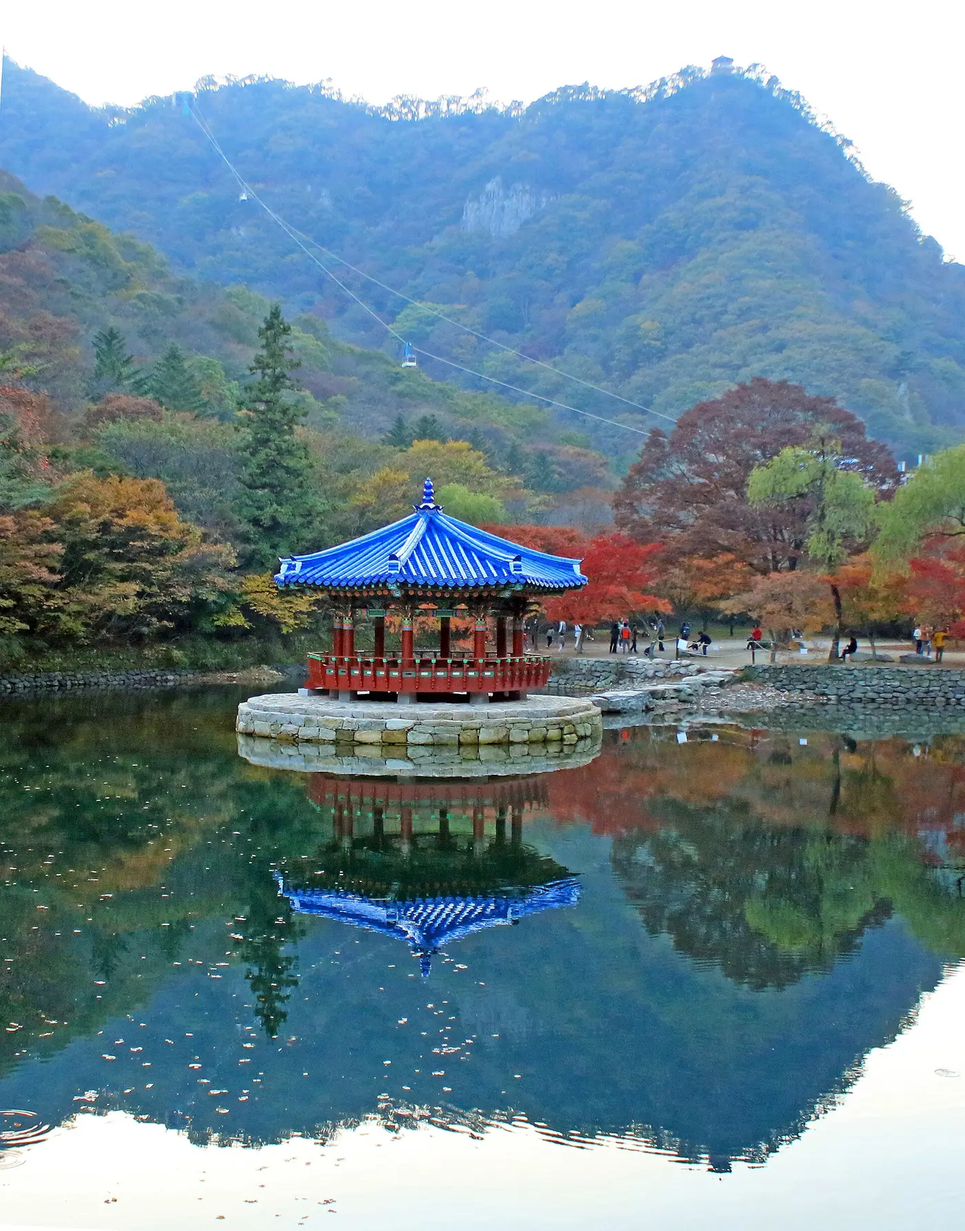 붉은 잎과 초록 잎이 섞인 산을 배경으로 연못 위 청기와 정자가 서 있는 내장산
