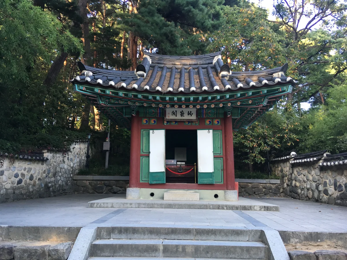 녹색 단청과 붉은 기둥의 작은 전각, 문이 열려 있고 현판이 걸려 있다
