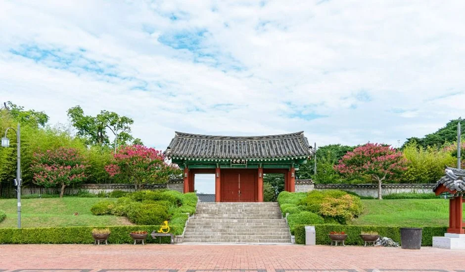 붉은 문과 돌계단, 배롱나무가 있는 강릉 오죽헌 경내의 전통 문