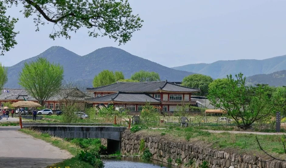 개울과 석축 너머로 산봉우리가 솟은 양동마을 풍경