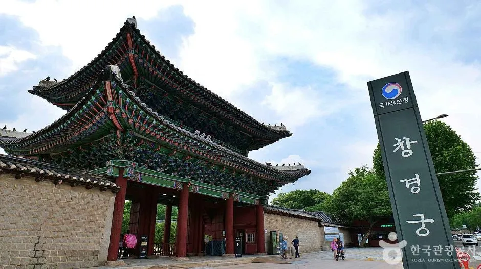 붉은 기둥과 단청 지붕을 얹은 창경궁 홍화문 정면에 안내 표지판이 보이는 모습
