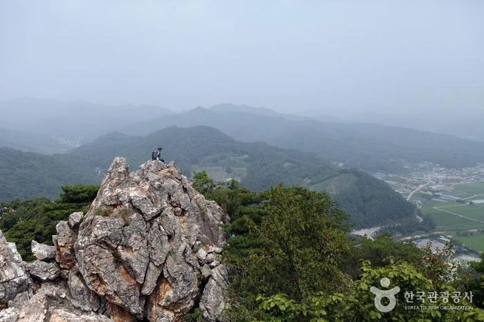 팔봉산 암봉 정상에 앉아 산줄기를 내려다보는 등산객
