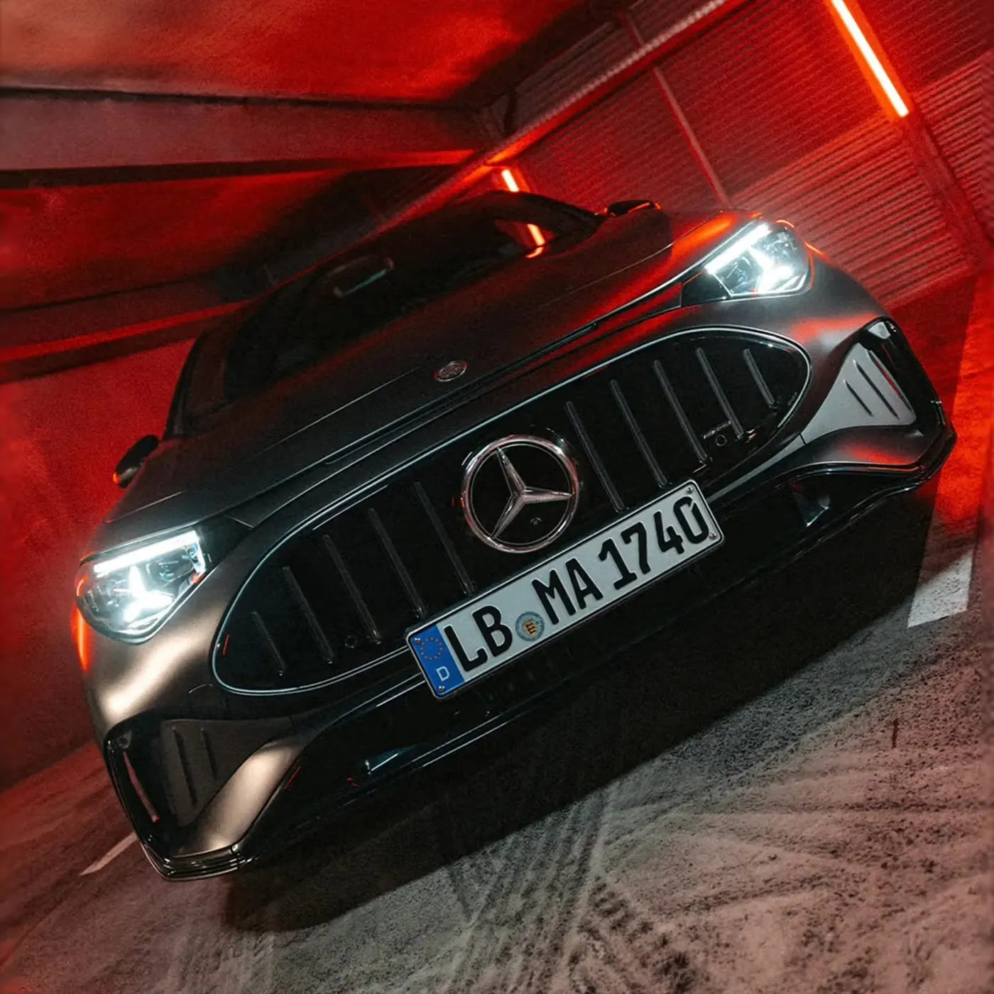 어두운 주차장에서 헤드램프를 밝힌 검은색 메르세데스-AMG CLA 45 전기차의 전면 모습