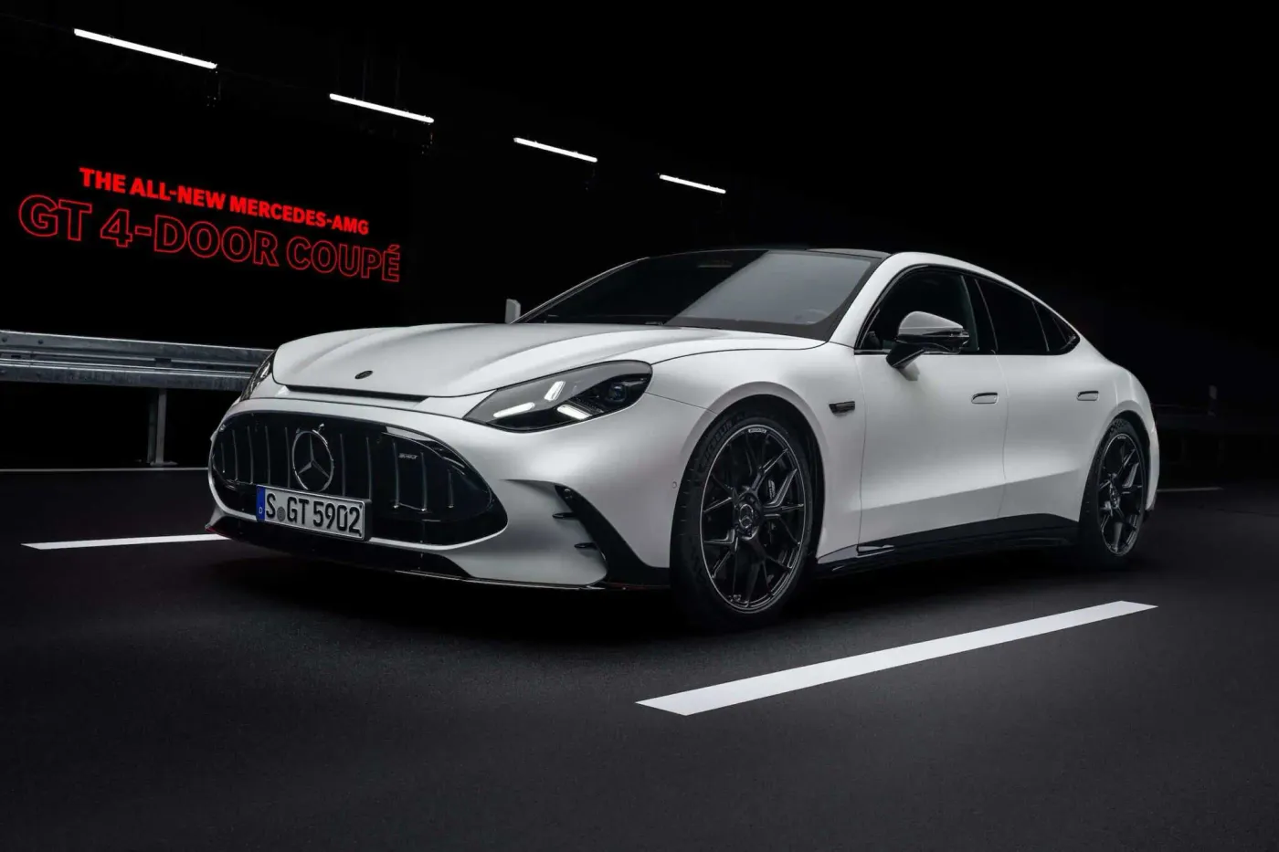 검은 도로 위에서 촬영된 흰색 메르세데스-AMG GT 4도어 쿠페의 전면 3/4 모습