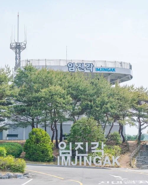 소나무 숲 뒤로 보이는 임진각 건물과 IMJINGAK 글자