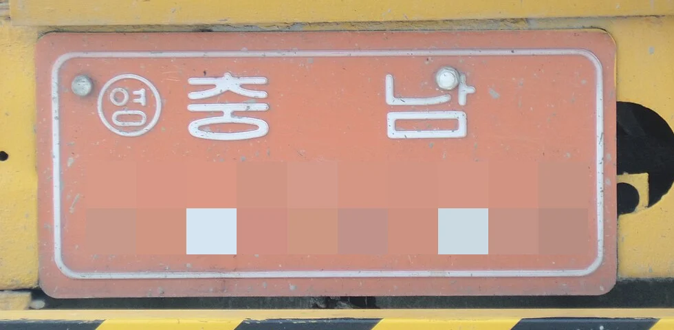 황색 건설기계 뒤쪽에 달린 주황색 바탕의 건설기계 대여사업용 등록번호표, 번호는 모자이크 처리