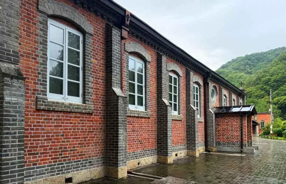 붉은 벽돌 벽과 아치 창이 이어진 풍수원성당 측면