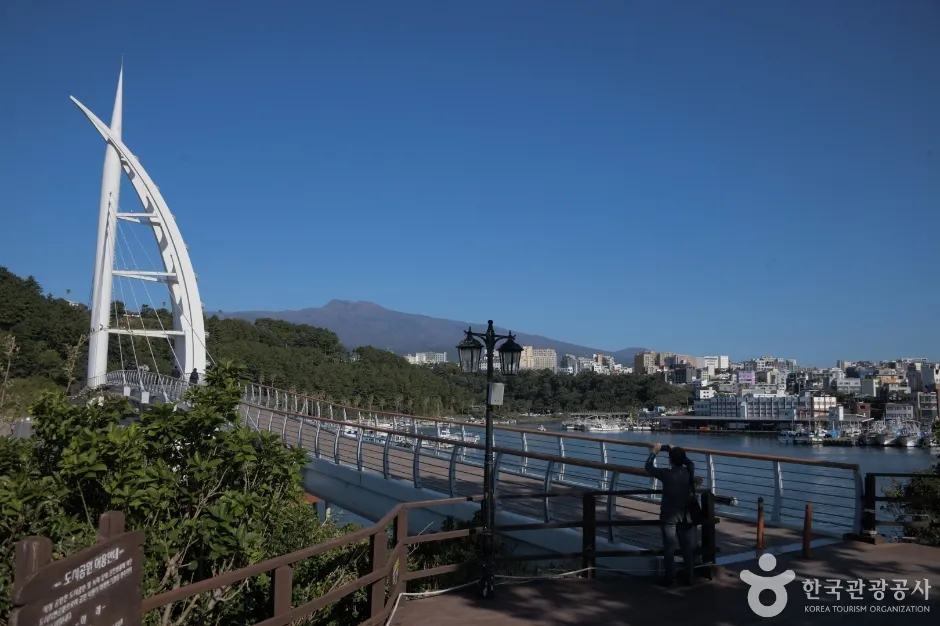 맑은 하늘 아래 흰 돛 모양 주탑이 있는 새연교와 멀리 보이는 산 능선