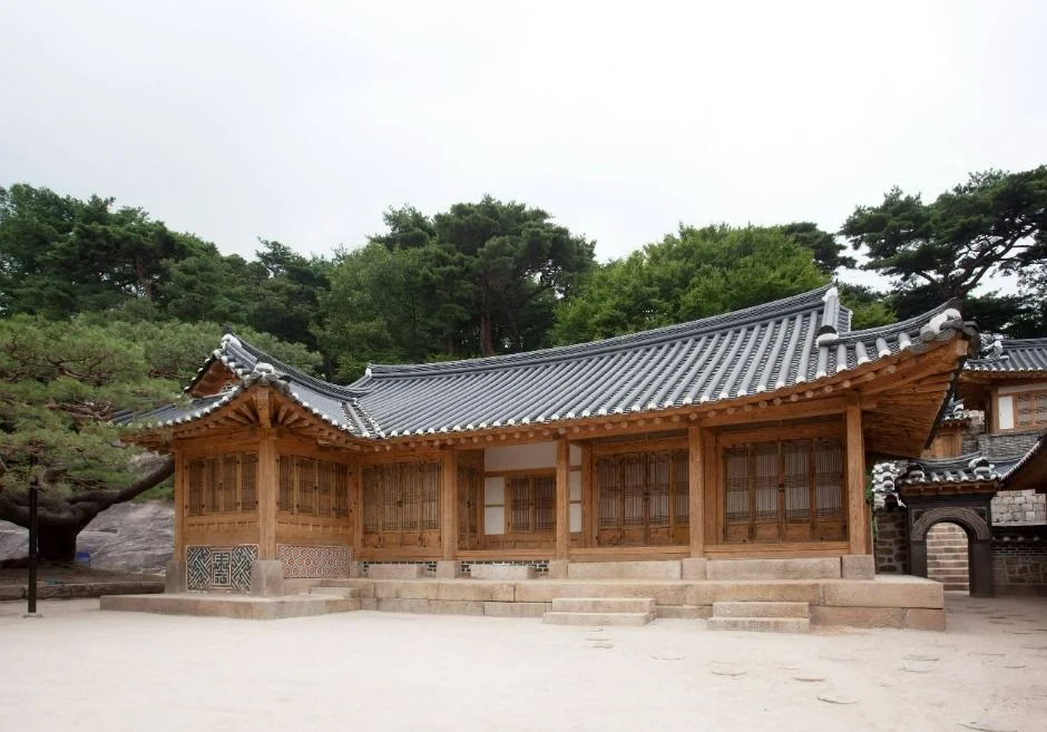 넓은 마당에서 본 기와지붕 한옥 건물과 뒤편 소나무