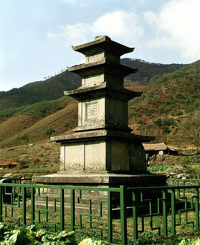 마른 풀빛 산비탈을 배경으로 선 성주사지 중앙 삼층석탑