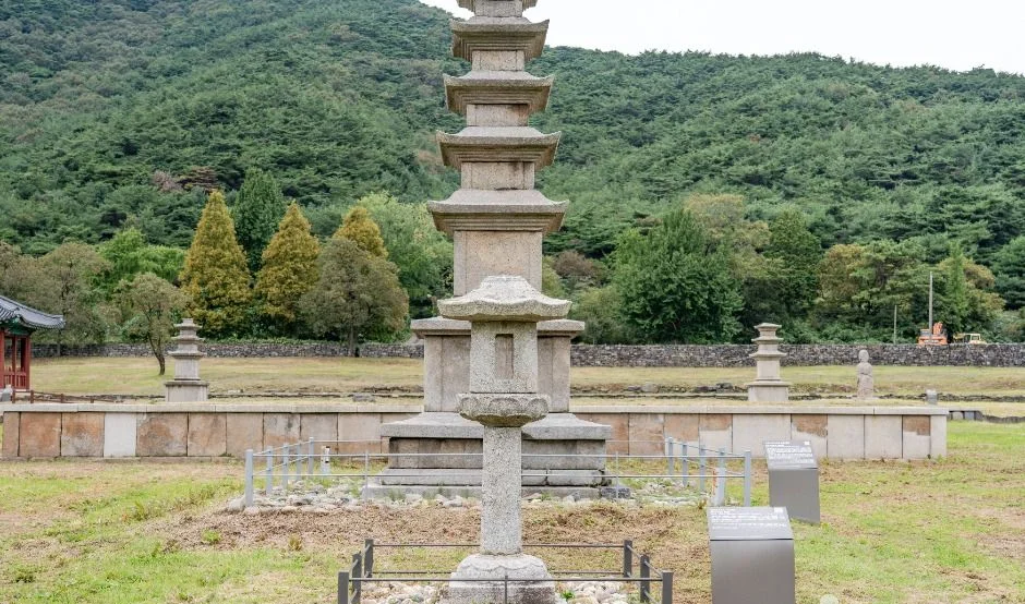 잔디밭 한가운데 서 있는 오층석탑과 뒤편의 녹색 산