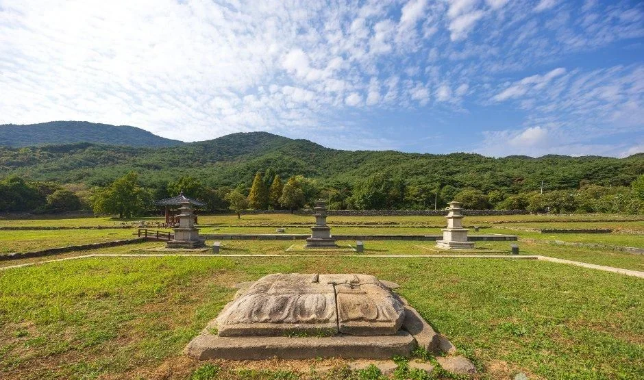 잔디 위에 놓인 석조연화대좌와 멀리 보이는 석탑