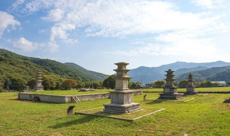 잔디 위에 석탑들이 줄지어 선 성주사지와 뒤편 산자락