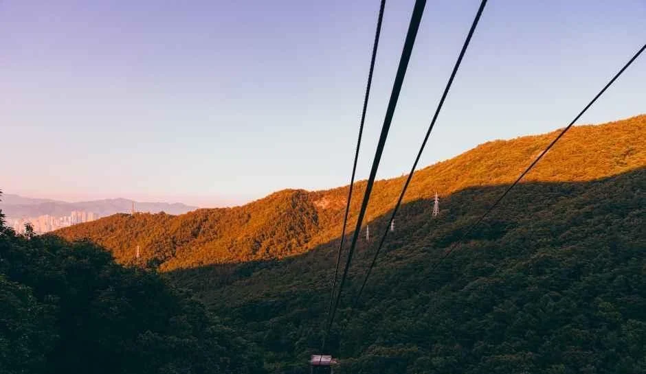 케이블카 줄 너머로 석양빛에 주황색으로 물든 앞산 능선