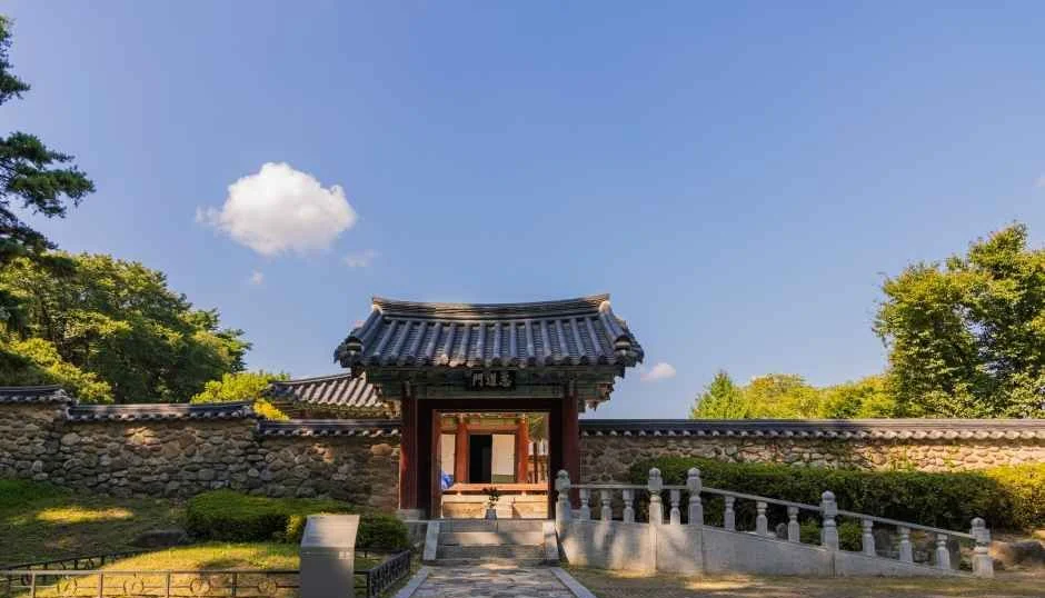 맑은 하늘 아래 돌담 사이로 기와 문이 서 있는 소수서원 경내 문
