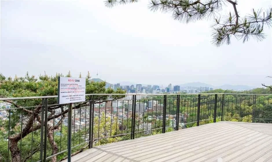 난간과 소나무 가지가 보이는 인왕산 무무대 전망대의 나무 데크 전망대