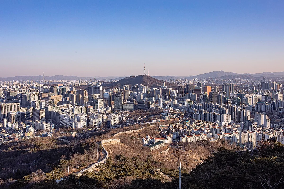 마른 산자락 위로 오솔길이 이어지고 멀리 남산과 도심이 보이는 인왕산 조망