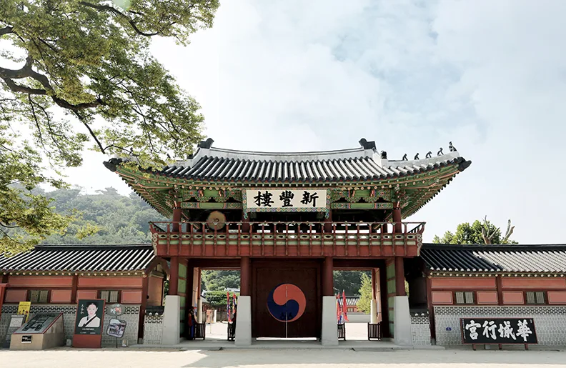 화성행궁 정문인 신풍루의 낮 전경, 태극 문양이 그려진 대문과 기와지붕이 보인다