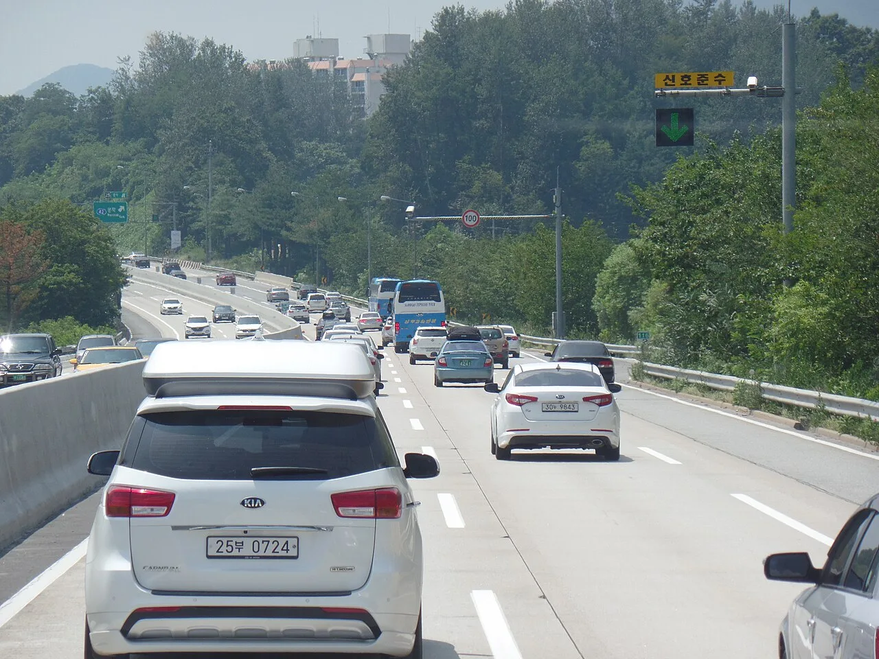 영동고속도로 문막IC 부근 전광판에 100km 제한속도 표지판과 무인단속카메라가 설치되고 신호준수 안내가 표시된 모습