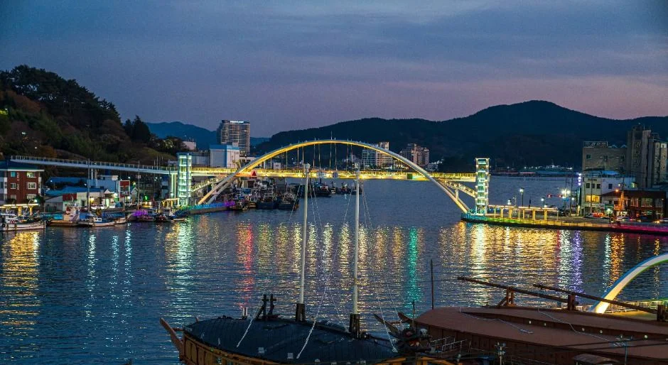 불 켜진 수변과 다리, 배가 보이는 항구 야경
