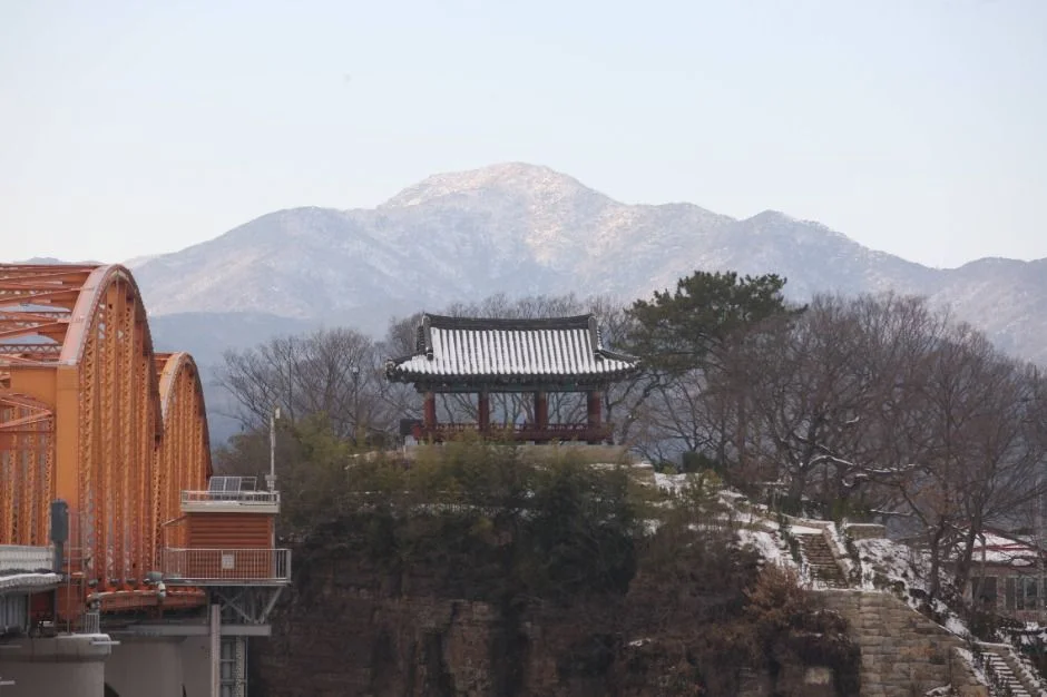 눈 덮인 산을 배경으로 한 정암루와 주황색 철교