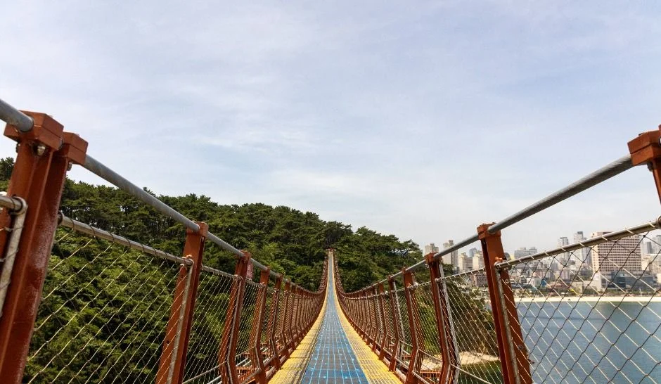 붉은 철제 케이블과 그물망 난간 사이로 바닥이 이어지는 대왕암공원 출렁다리 위