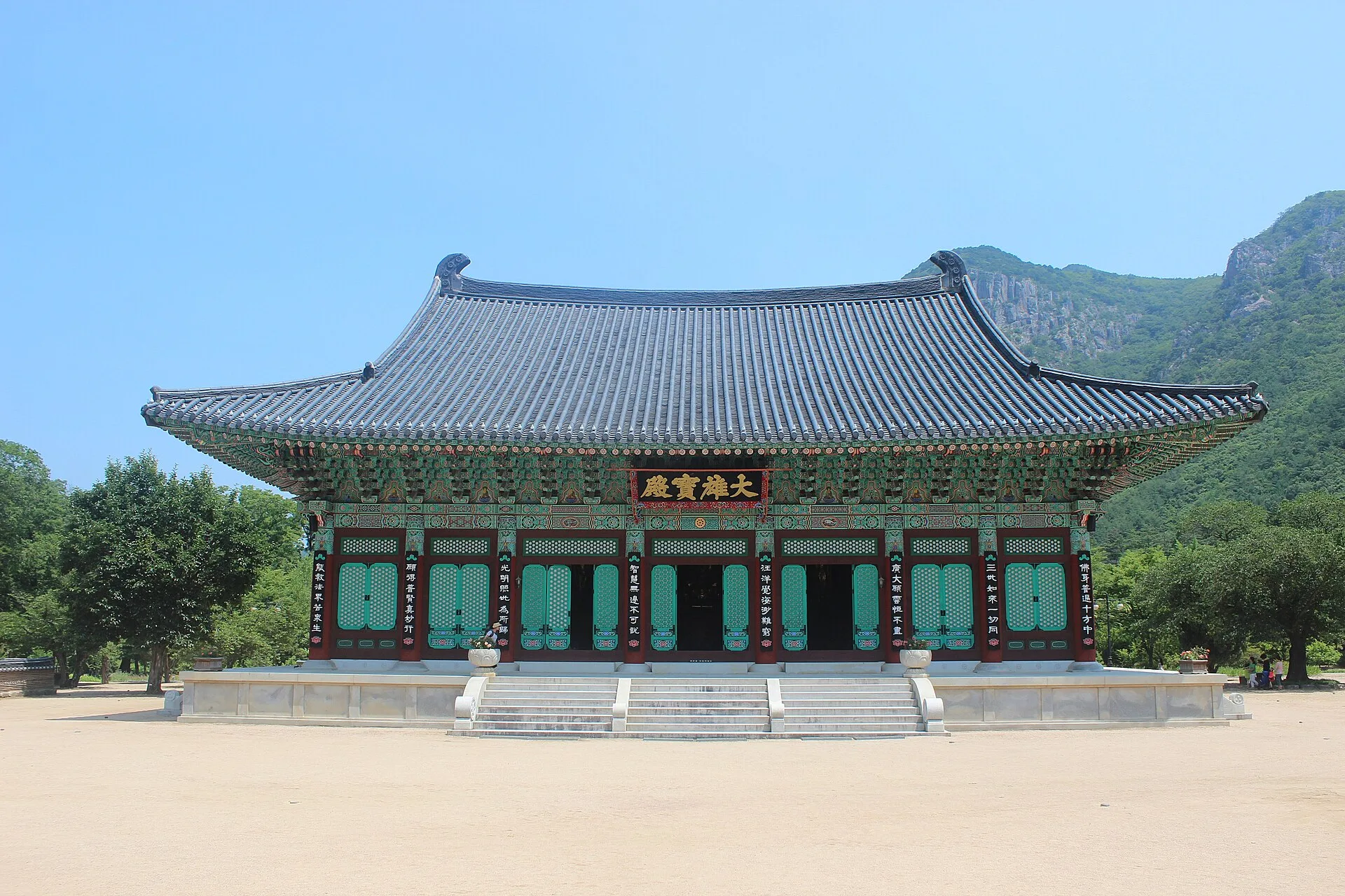 푸른 산을 배경으로 넓은 앞마당 너머에 서 있는 운문사 대웅전