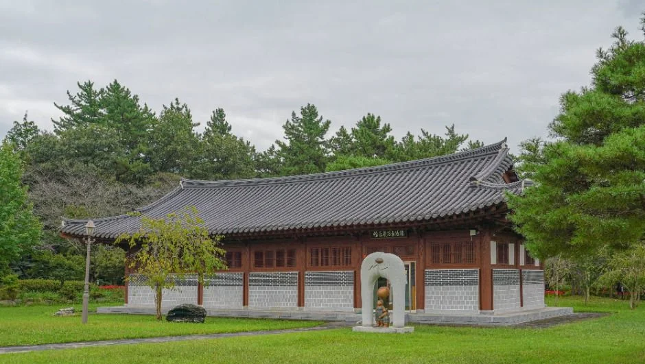잔디밭 너머로 긴 목조 한옥 건물이 보이는 풍경