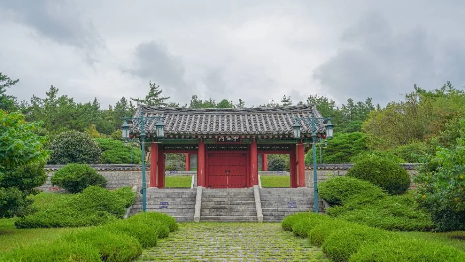 계단 위 붉은 기둥의 문과 지붕이 보이는 진입로
