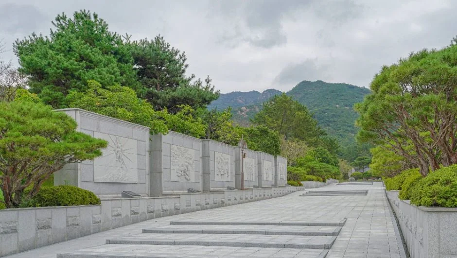 경사진 통로를 따라 이어지는 회색 석벽 패널과 계단
