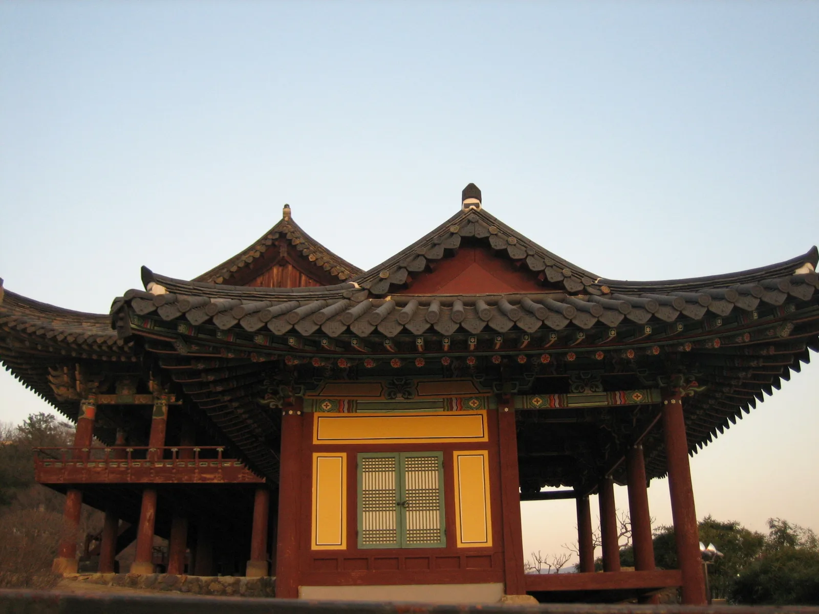 저녁 하늘을 배경으로 겹쳐진 전통 누각의 처마와 단청이 보이는 모습