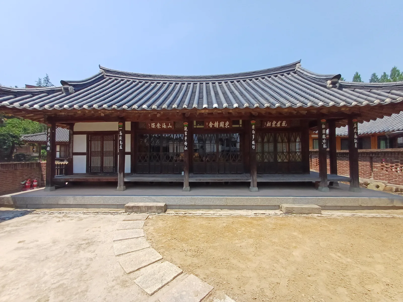 팔작지붕을 얹은 한옥 사랑채, 처마 아래 한자 현판이 여러 개 걸려 있다