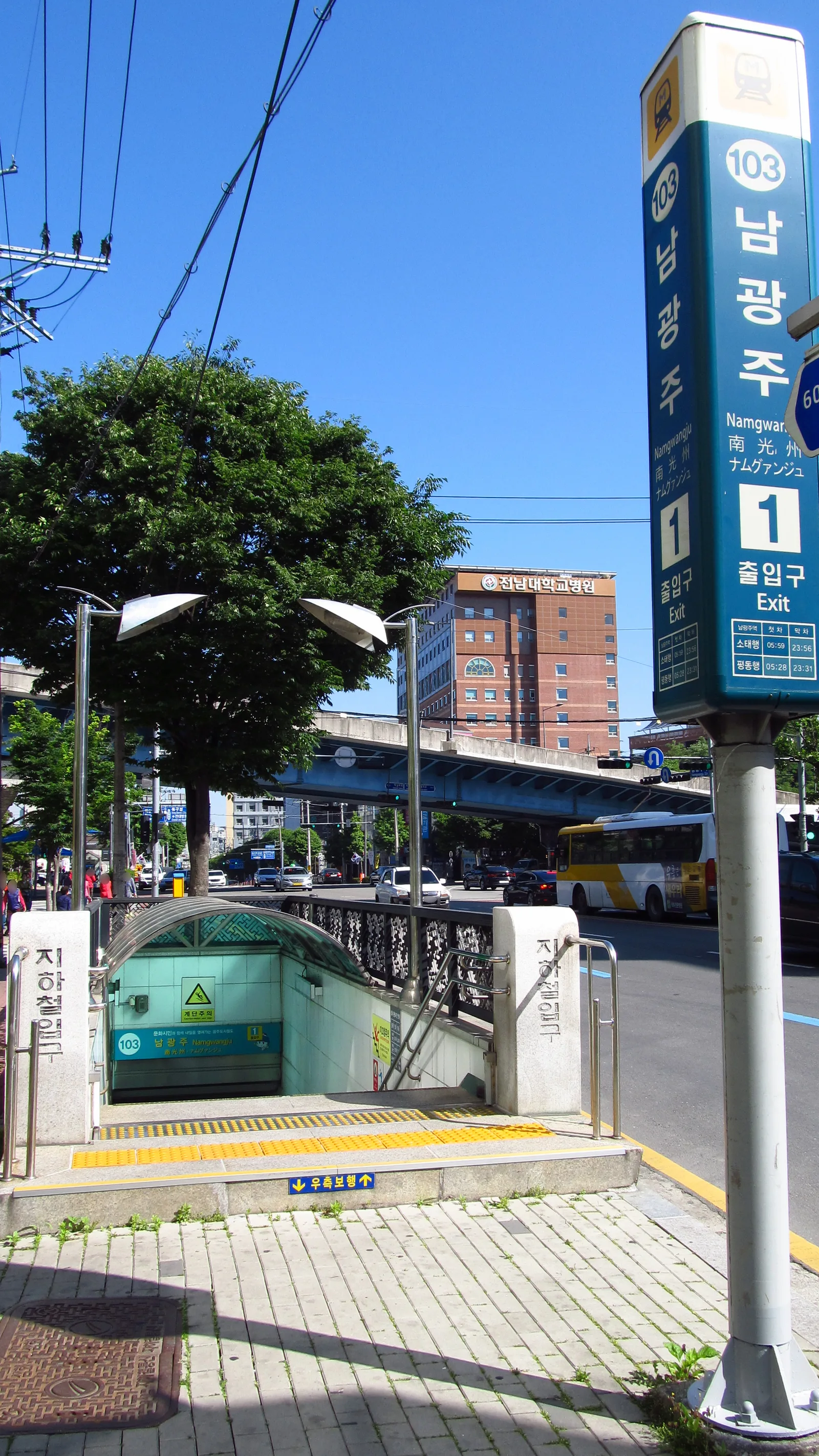 파란색 남광주역 표지판이 세워진 지하철 출입구, 뒤로 고가도로와 버스가 지나는 도로가 보인다