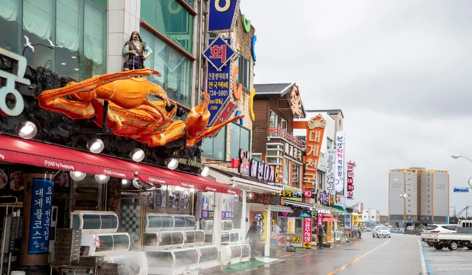 큰 게 조형물이 올려진 건물과 상점이 늘어선 강구항 대게거리 풍경