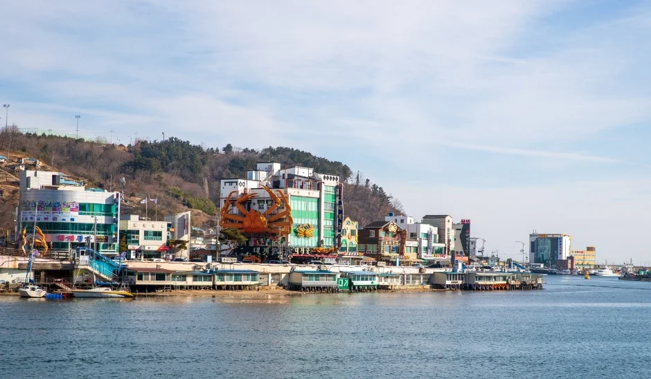 항구 건너편에 대게 모양 간판이 달린 건물이 보이는 풍경